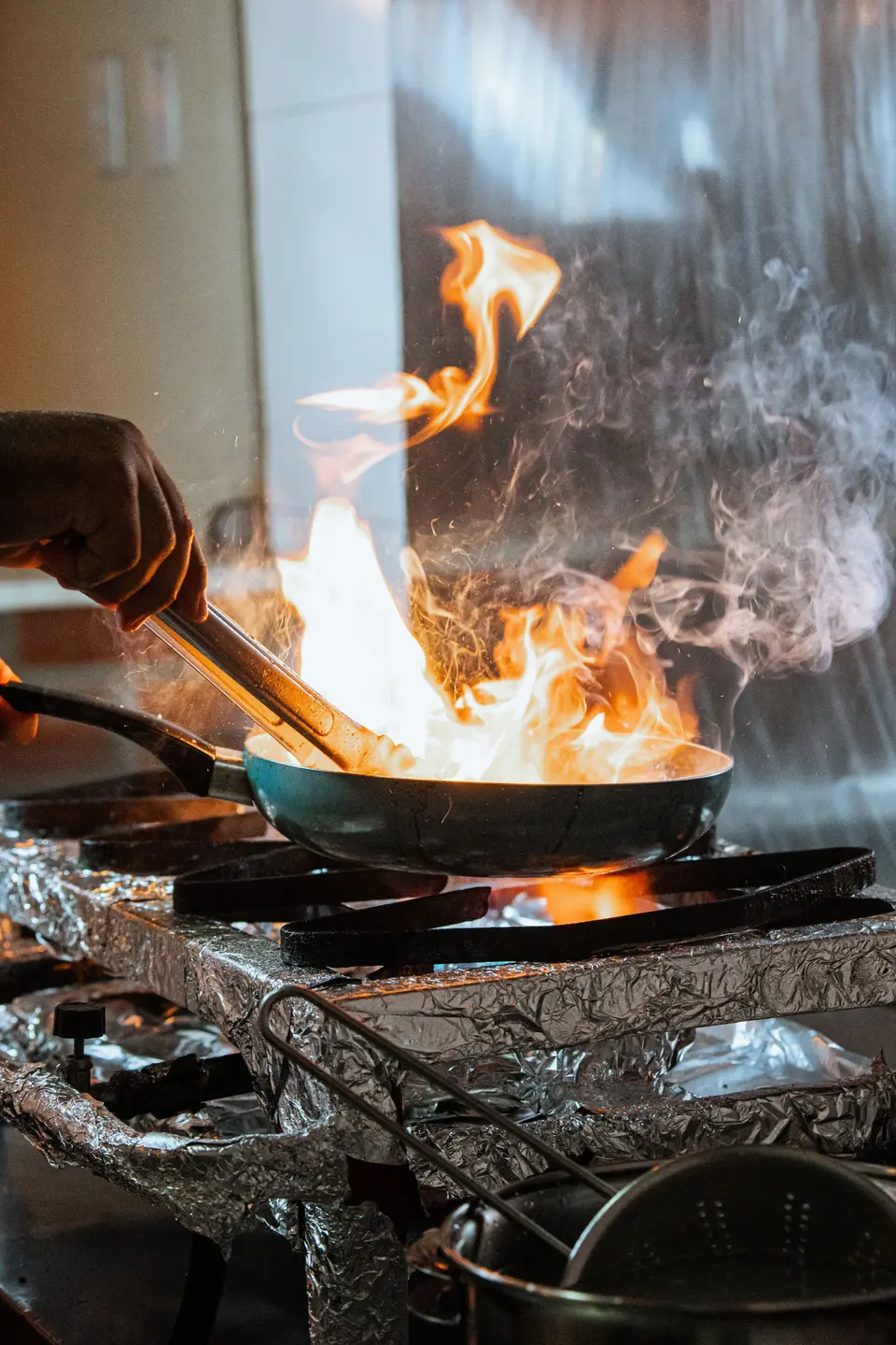 A pan catching a burst of flame on a kitchen range